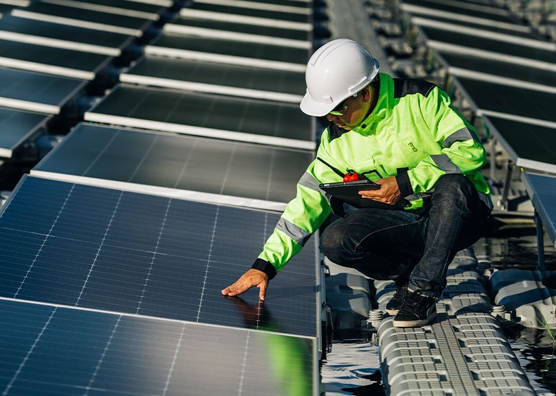 SolarMaxx installer in hi-vis checking a rooftop solar panel with a tablet